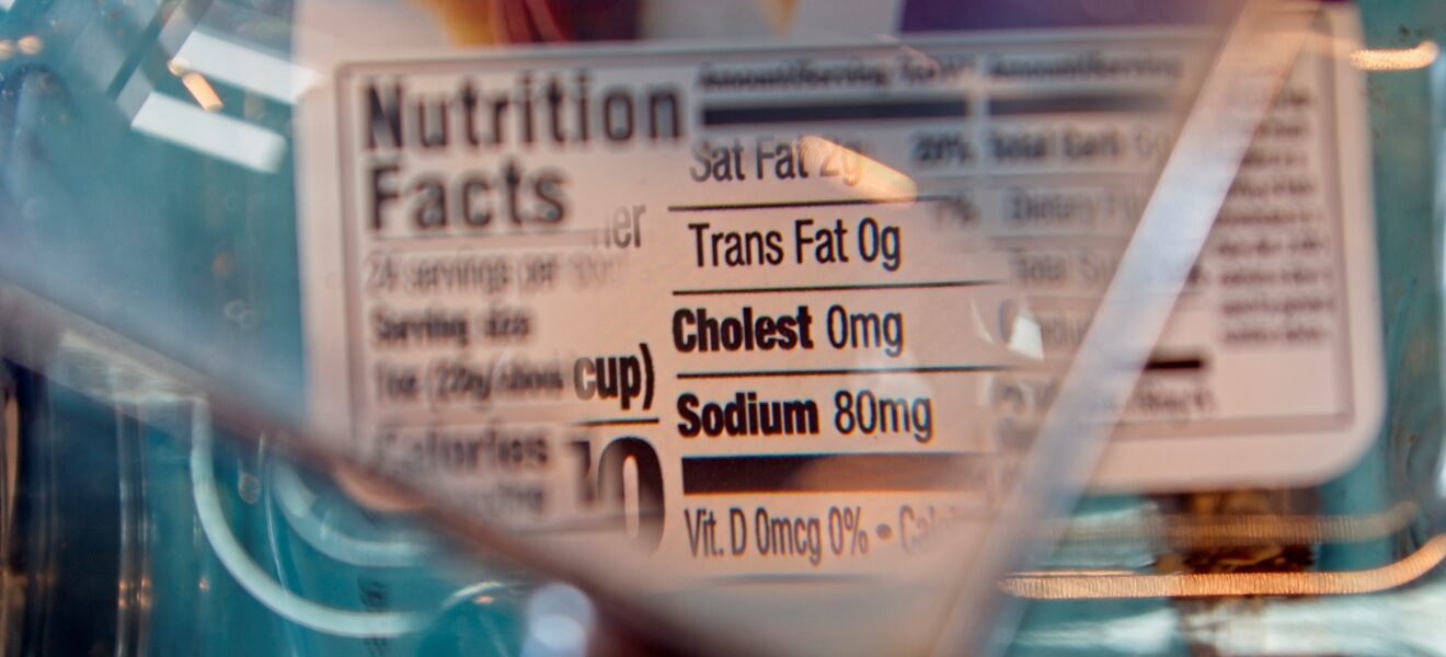 Magnifying glass focusing on cholesterol and sodium on a food label.