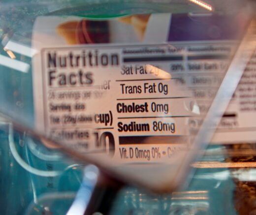 Magnifying glass focusing on cholesterol and sodium on a food label.