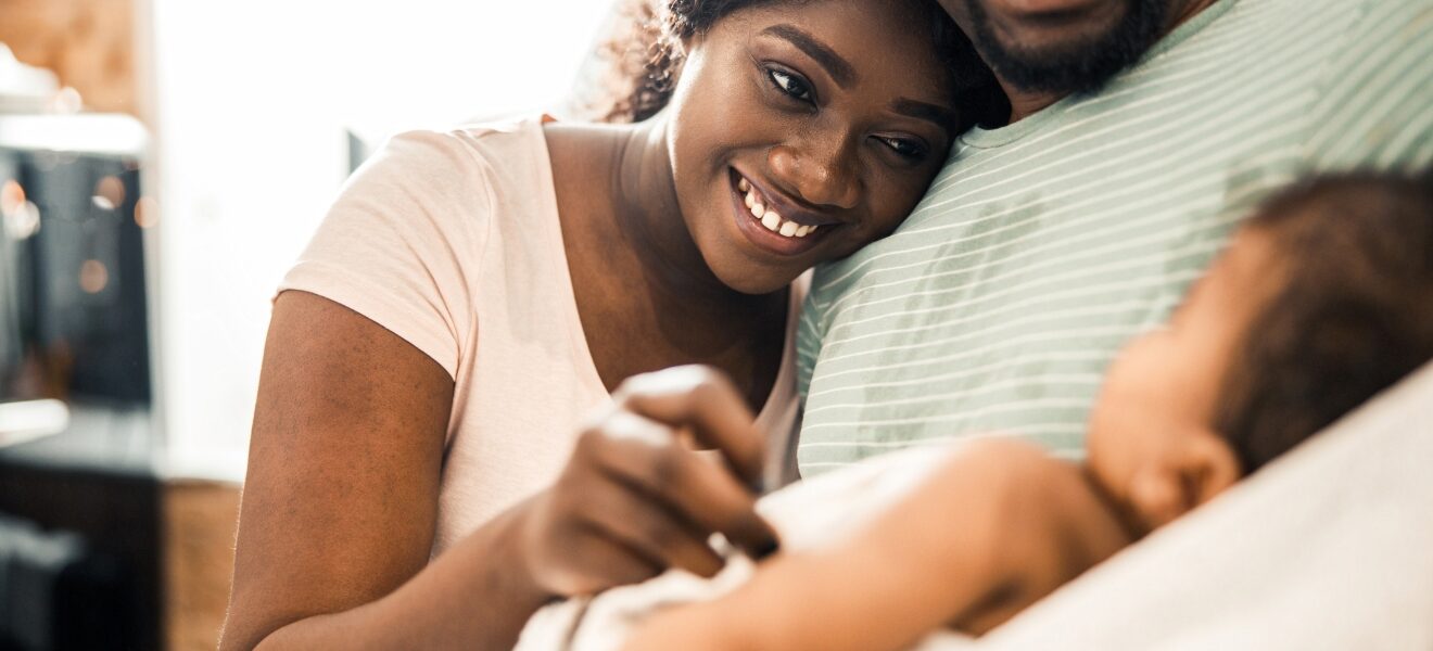 A mother and father smile at their infant.