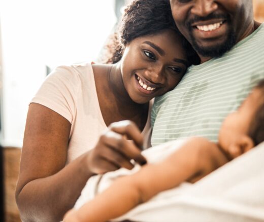 A mother and father smile at their infant.