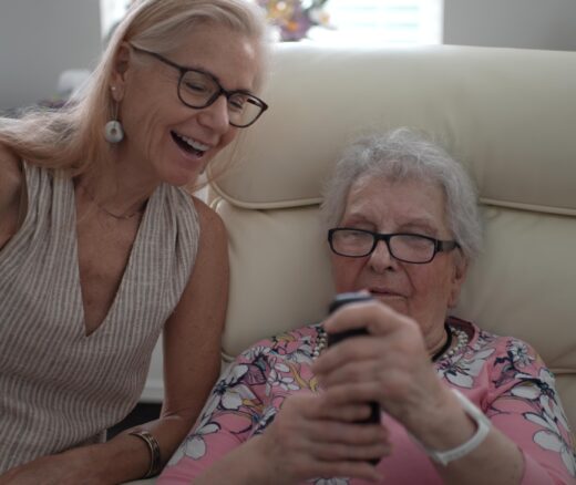 Smiling daughter helps elderly mother with phone