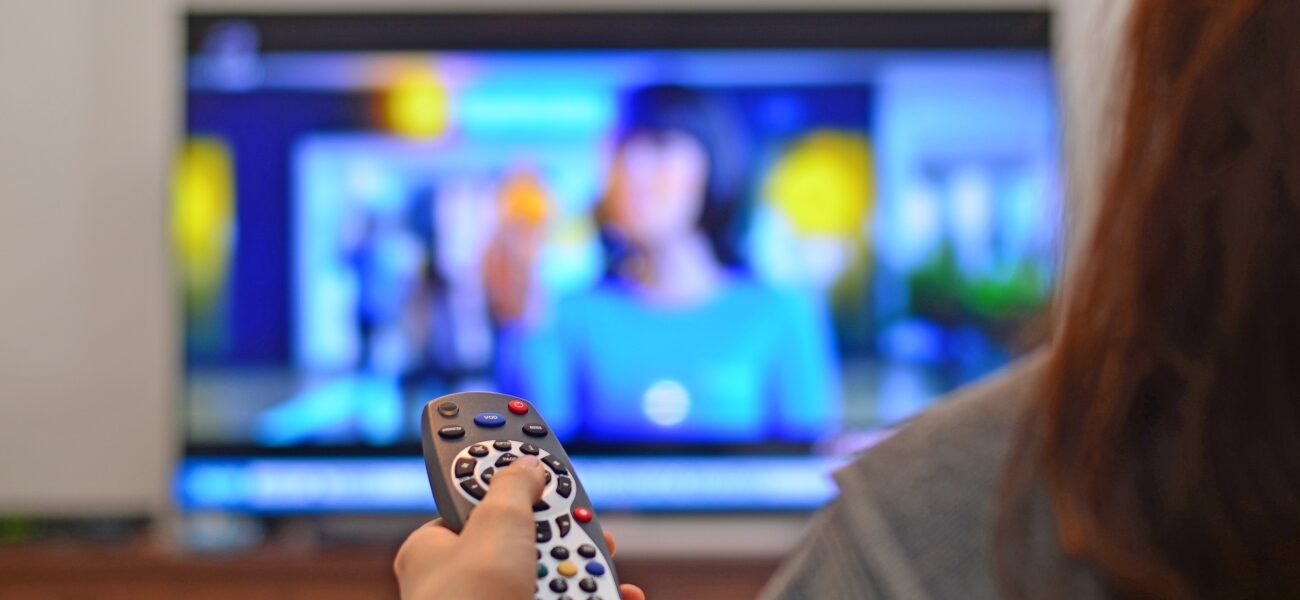 Woman watching tv and using remote controller.