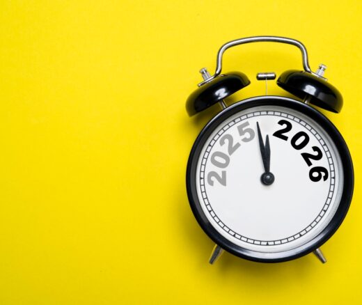 An alarm clock showing the transition from 2025 to 2026 on a yellow background.