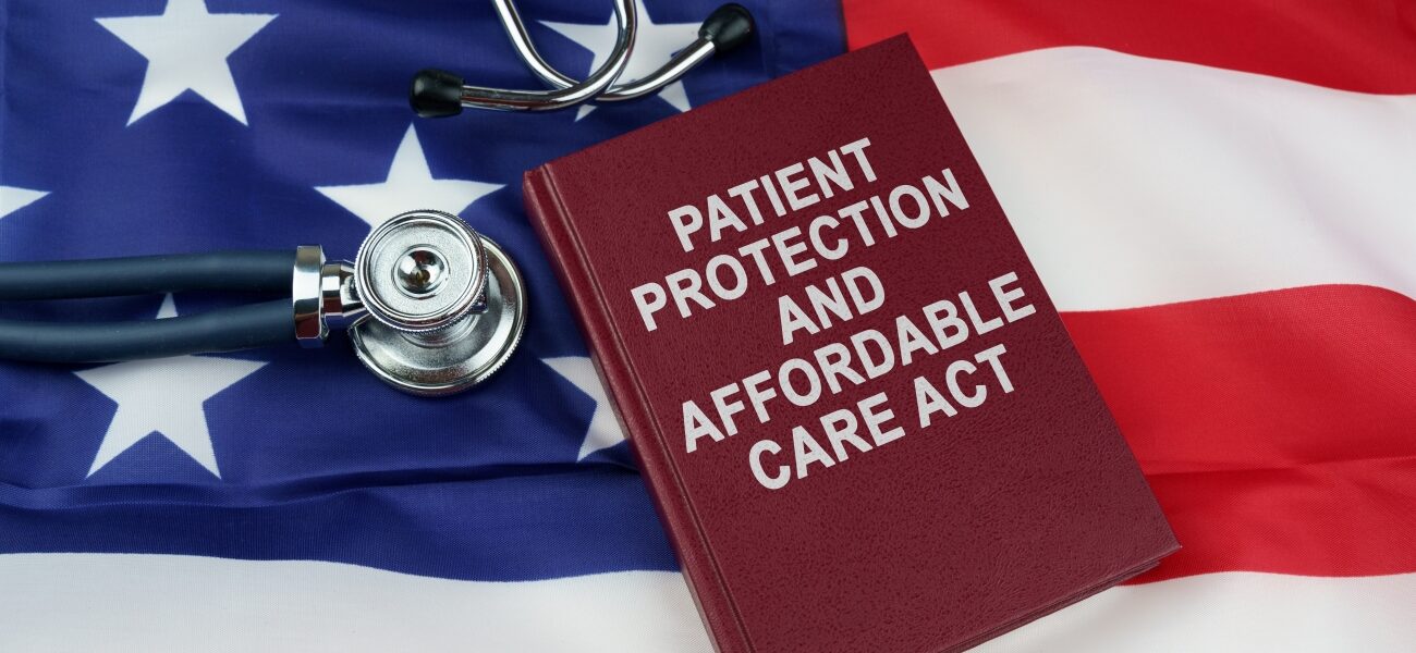 A book titled Patient Protection and Affordable Care Act with a stethoscope, both on top of an American flag.
