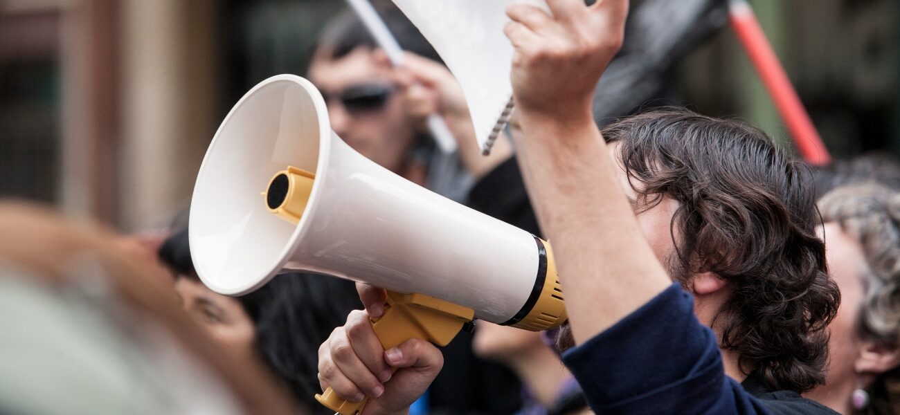 Person with a megaphone holding a sign.