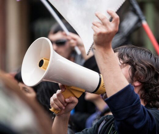 Person with a megaphone holding a sign.