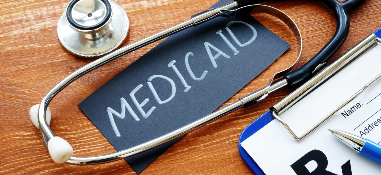 Sign that says Medicaid circled by a stesthoscope and next to a clipboard.