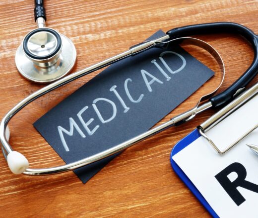 Sign that says Medicaid circled by a stesthoscope and next to a clipboard.