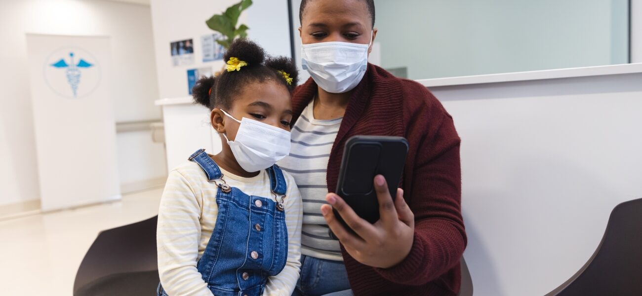 Black mother and child wearing masks in a doctor's office waiting room.