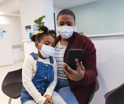 Black mother and child wearing masks in a doctor's office waiting room.