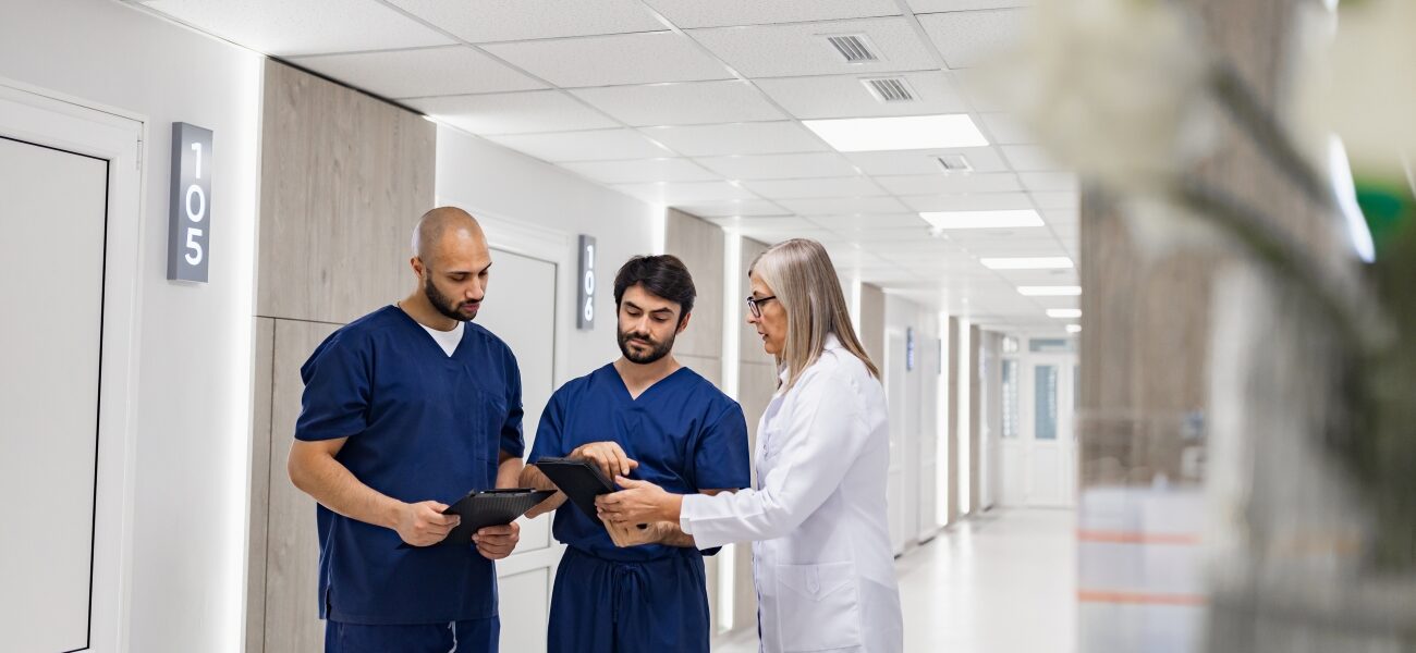 Two nurses with a doctor in a hospital hallway.