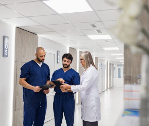 Two nurses with a doctor in a hospital hallway.