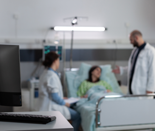 Nurse and doctor in the blurred background with a desktop computer in focus.