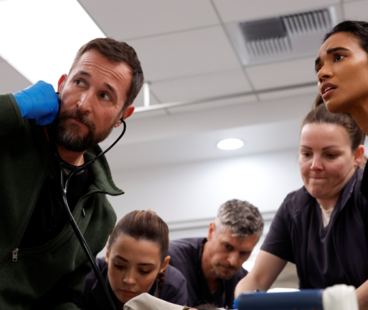Noah Wyle, Ned Brower, and Supriya Ganesh in a still of the Pitt, treating a patient.