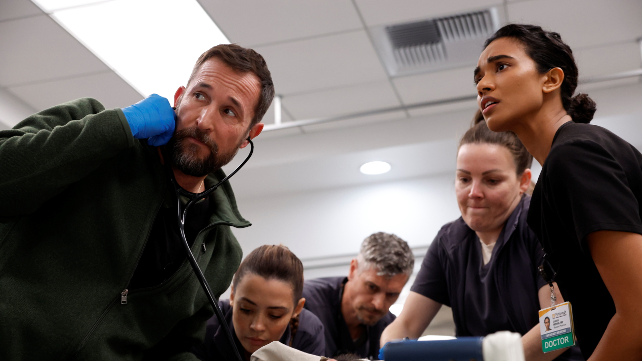 Noah Wyle, Ned Brower, and Supriya Ganesh in a still of the Pitt, treating a patient.