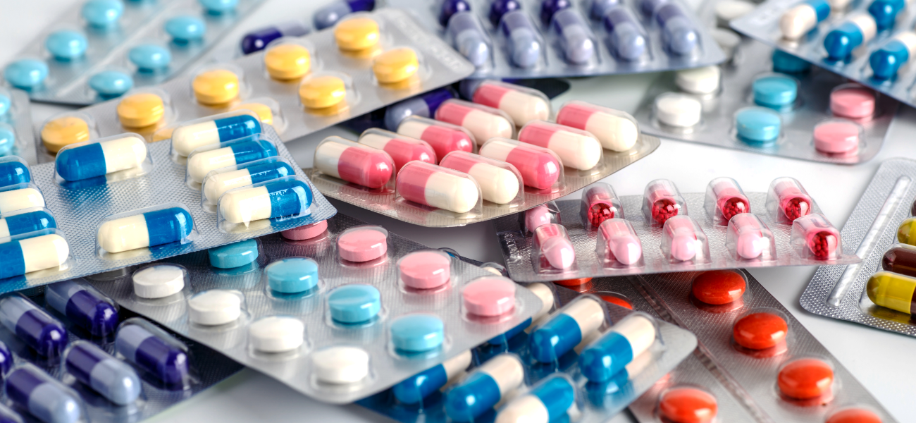 About 10 packs of prescription medicine laying in a pile in varying colors.