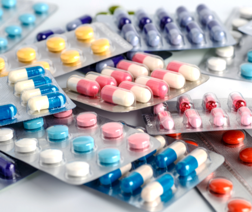 About 10 packs of prescription medicine laying in a pile in varying colors.