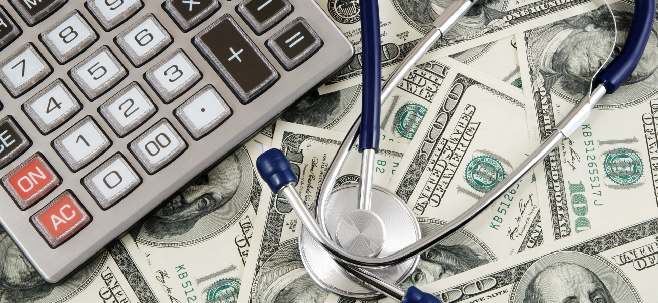 $100 bills under a calculator and stethoscope