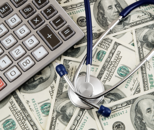 $100 bills under a calculator and stethoscope