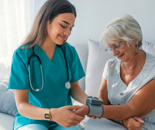 A nurse measuring an elderly woman's blood pressure sitting on a couch.