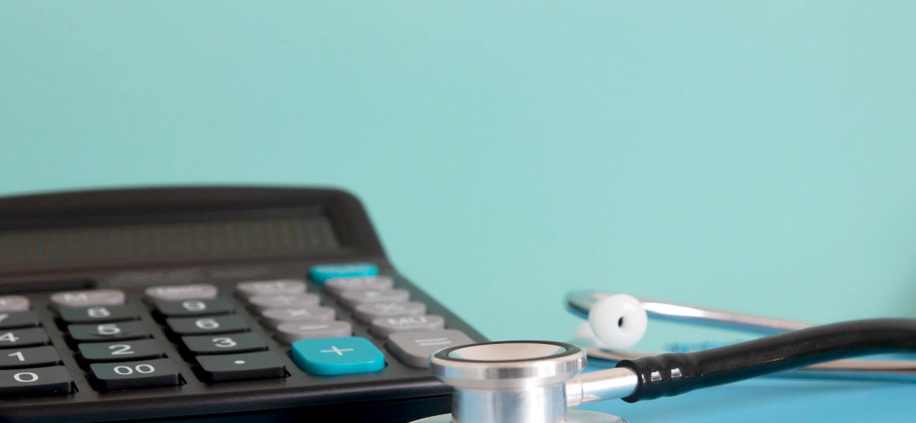 A calculator next to a stethoscope on a blue table and background.