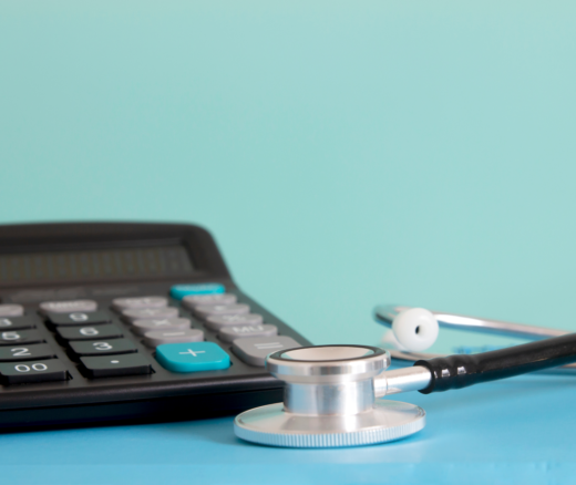 A calculator next to a stethoscope on a blue table and background.