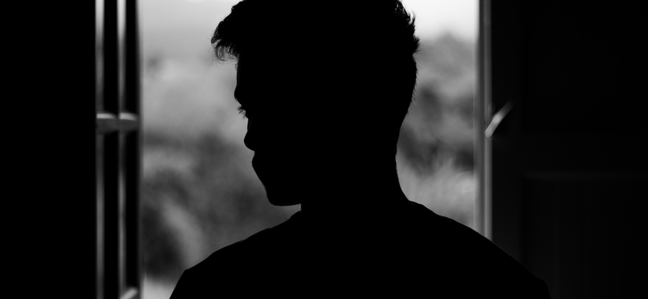 A man's black silhouette at the window, in black and white.