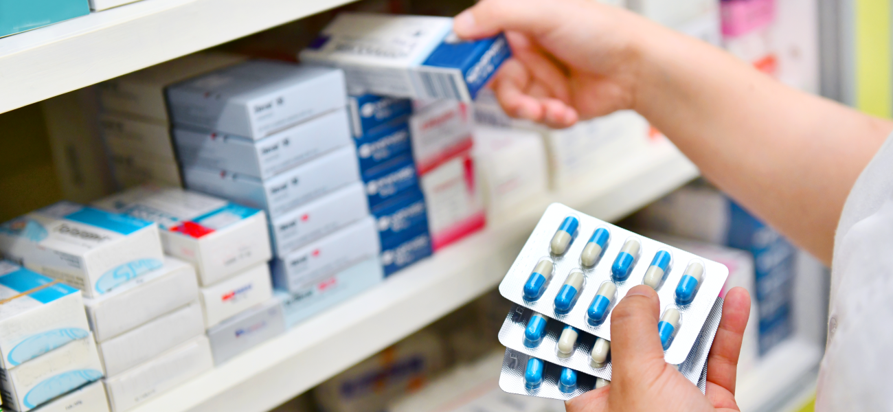 A person stocking a shelf with medicines.