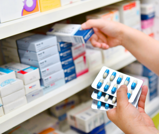 A person stocking a shelf with medicines.