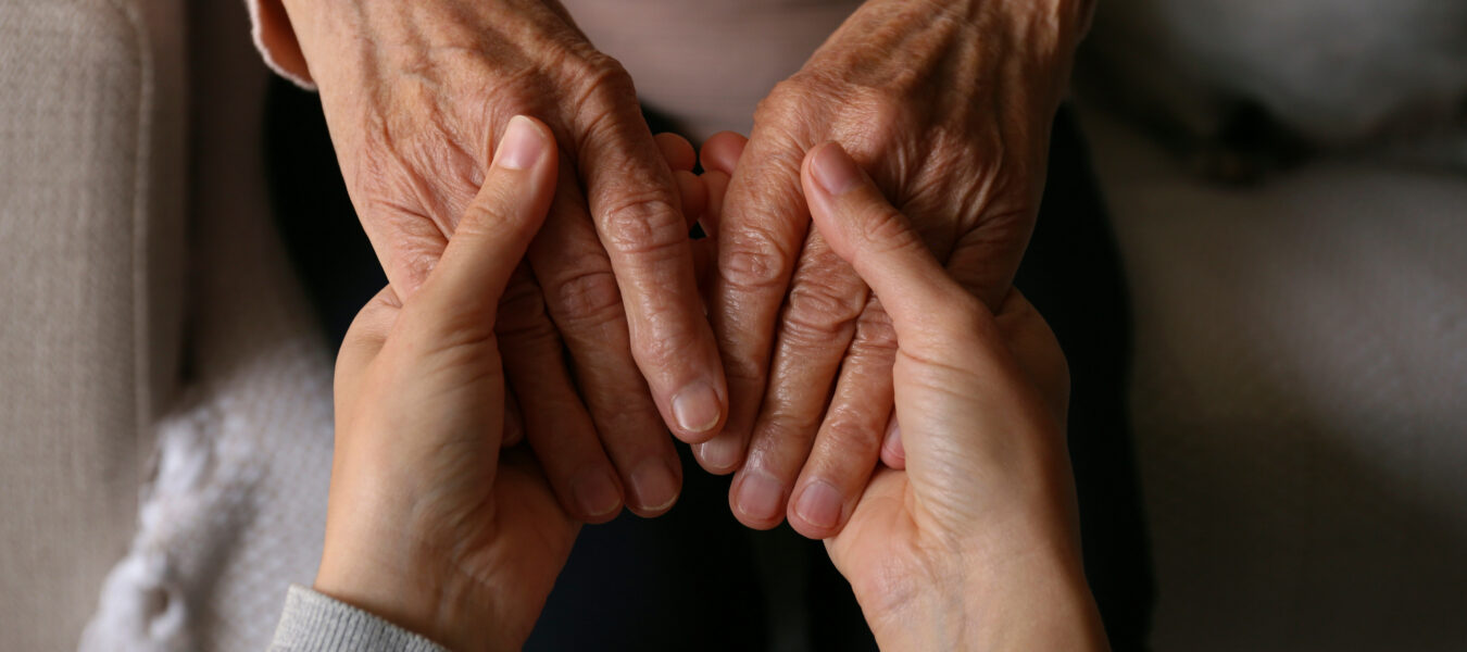 An elderly woman and female geriatric social worker holding hands