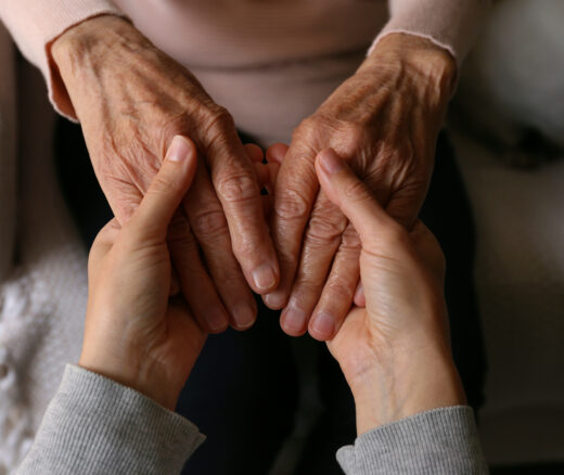 An elderly woman and female geriatric social worker holding hands