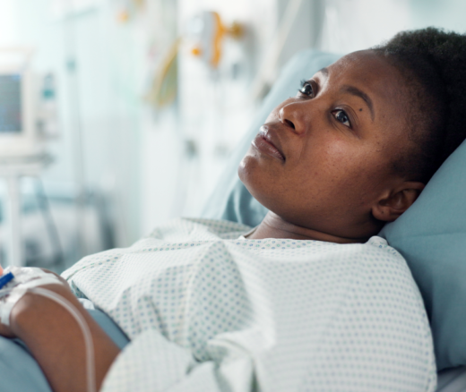 A Black woman laying in a hospital bed.