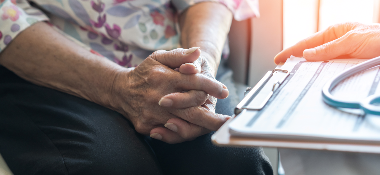 A close up of a patient's hands next to a clipboard