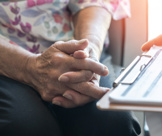 A close up of a patient's hands next to a clipboard