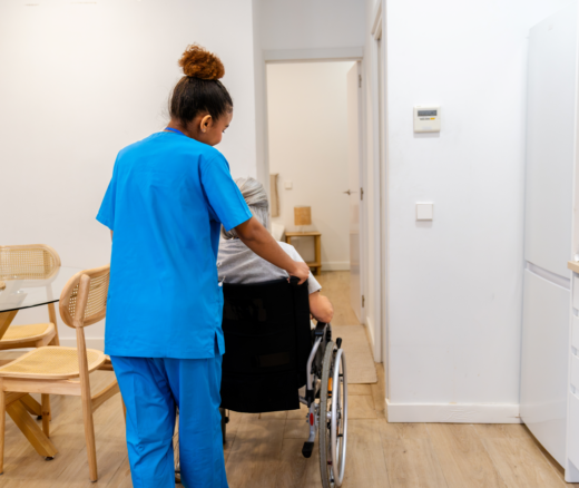 A nurse pushing an elderly person in their wheelchair